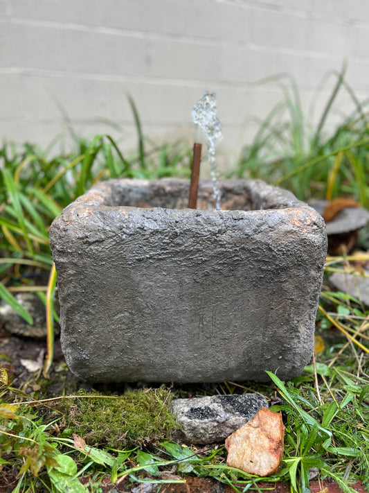Cement fountain with water feature in a garden setting