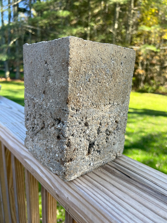Concrete block on a wooden surface with a blurred natural background