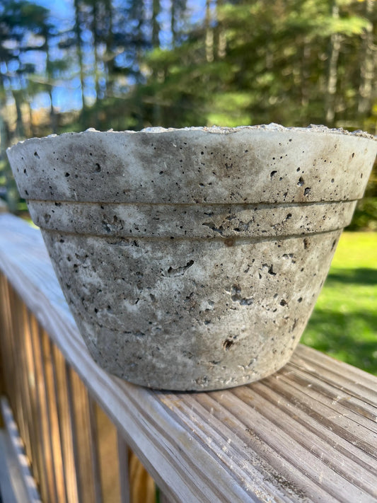 Concrete pot on a wooden railing with a blurred natural background