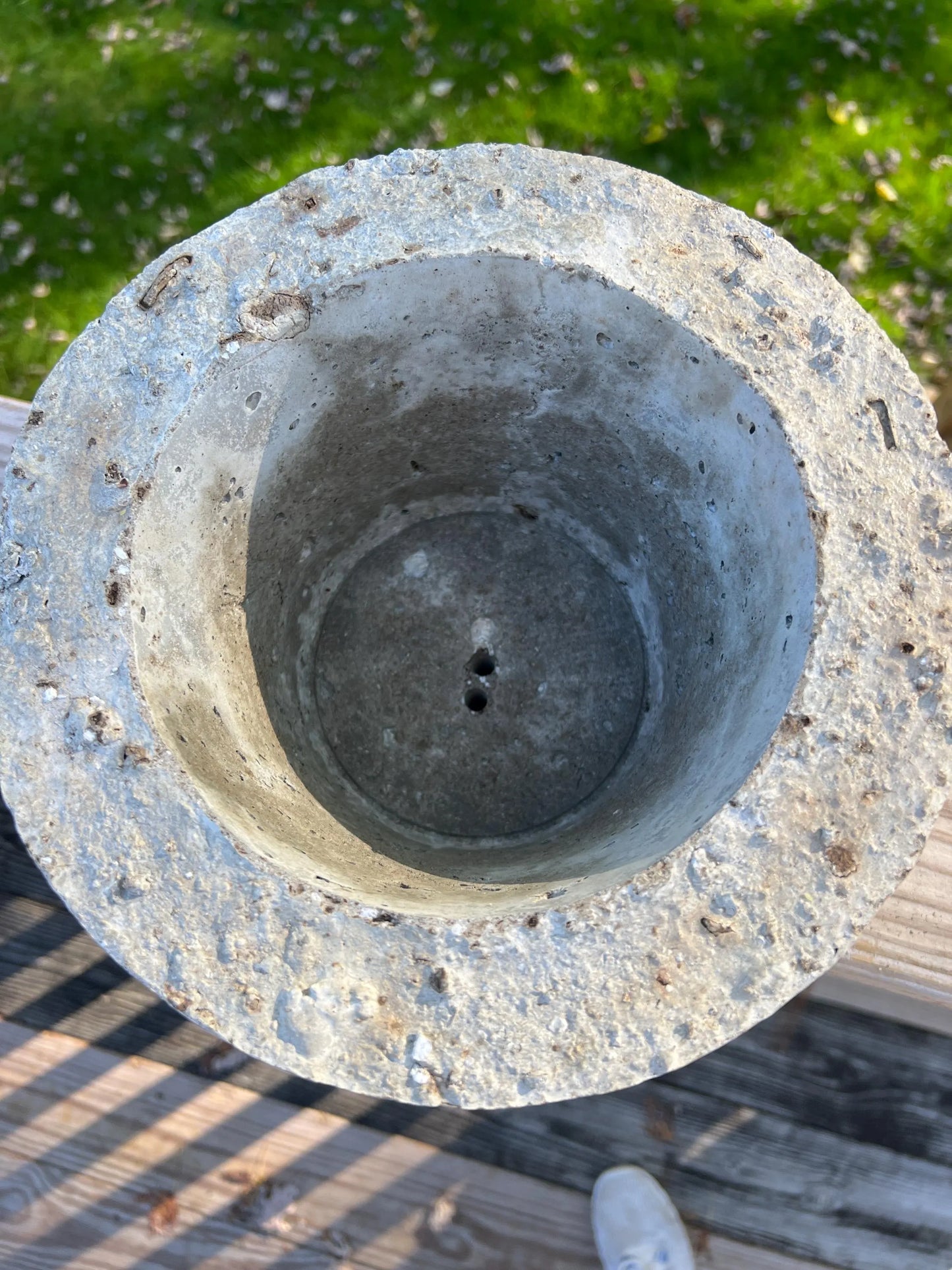 Concrete flower pot with a central hole on a grassy background