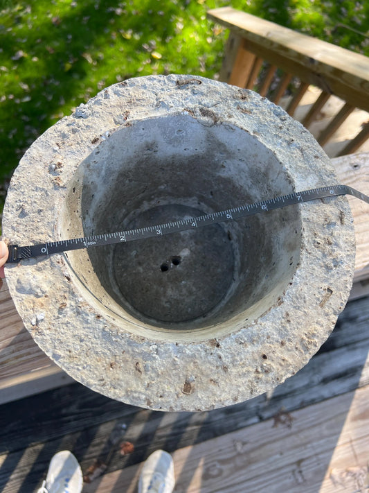 Concrete or stone object with a ruler for scale on a wooden surface