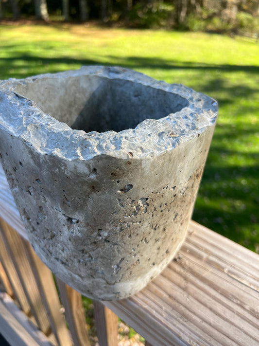 Concrete planter on a wooden surface with grass and trees in the background