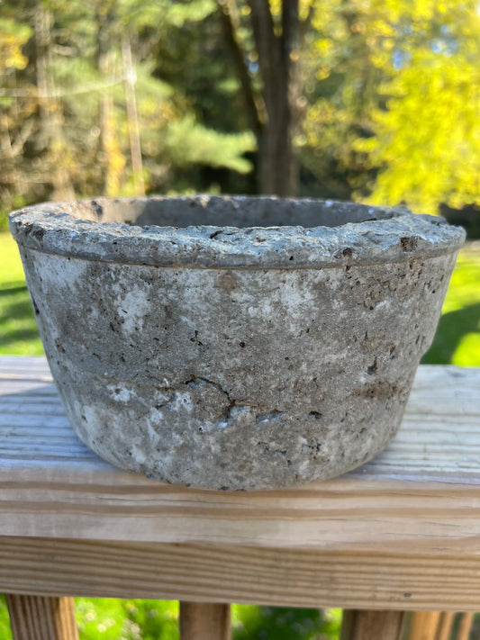 Concrete pot on a wooden surface with a blurred natural background
