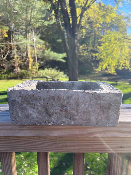 Rectangular stone planter on a wooden deck with trees in the background