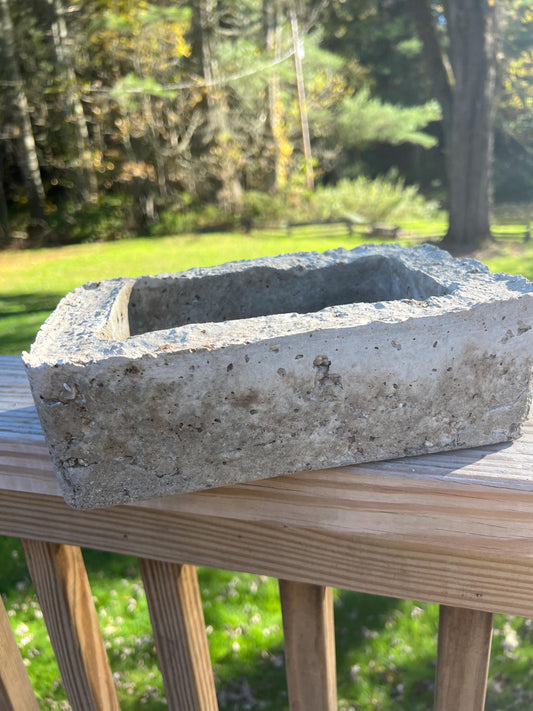 Concrete planter box on a wooden deck with a blurred natural background