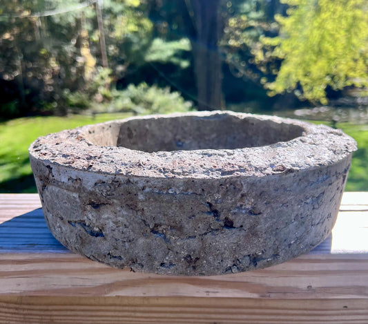 Concrete basin on a wooden surface with a blurred natural background