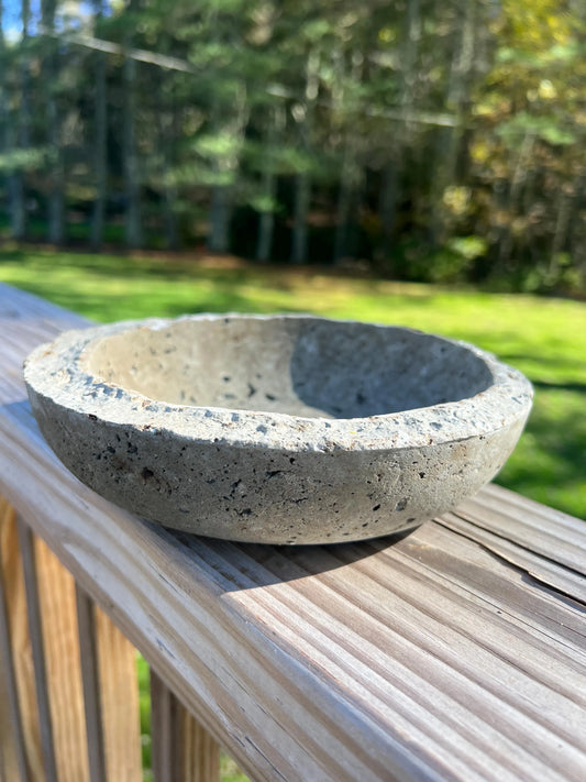 Concrete bowl on a wooden surface with a blurred natural background