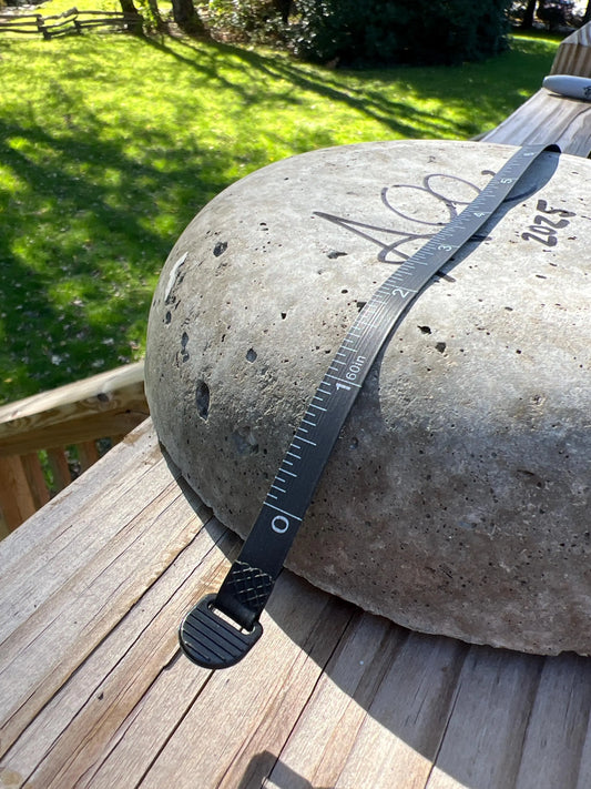 Black measuring tape on a large stone object outdoors