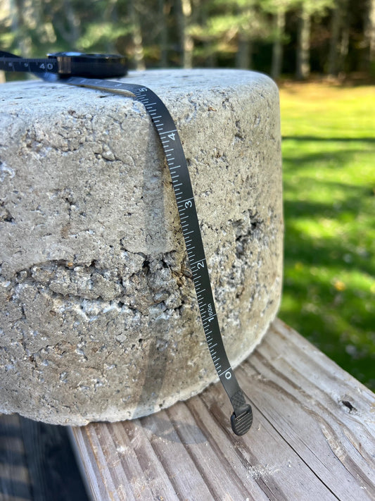 Tape measure on a concrete block with a grassy area in the background